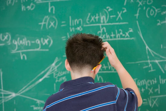 A boy scratching his head at math written on a chalkboard