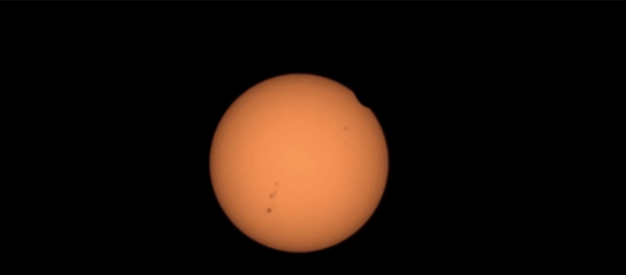 A silhouette of the Martian moon Phobos passes across the face of the Sun.