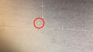 A grainy target display screen showing a small rounded light near the target