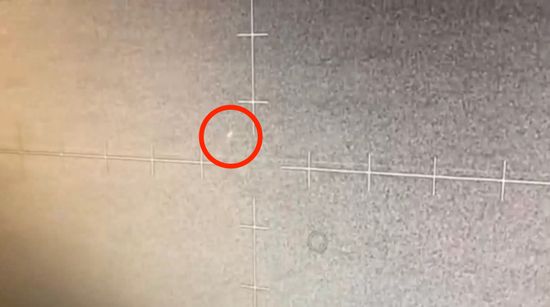 A grainy target display screen showing a small rounded light near the target.