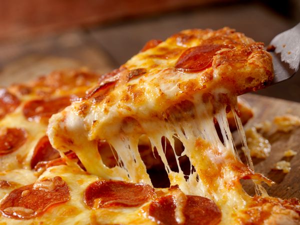 A slice of pepperoni pizza being pulled from a pie