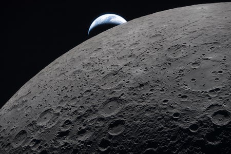 The crescent Earth sets against the shadowy, cratered limb of the moon.