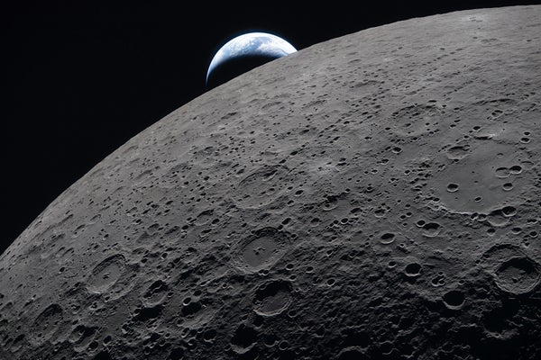 The crescent Earth sets against the shadowy, cratered limb of the moon.