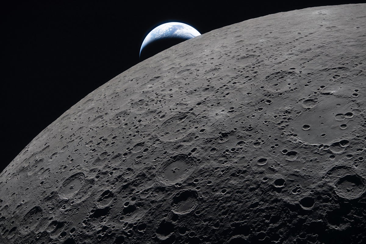 The crescent Earth sets against the shadowy, cratered limb of the moon.