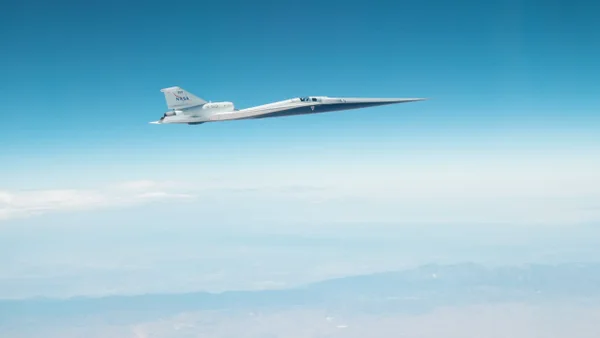 A sleek white plane speeds ahead in a blue sky.