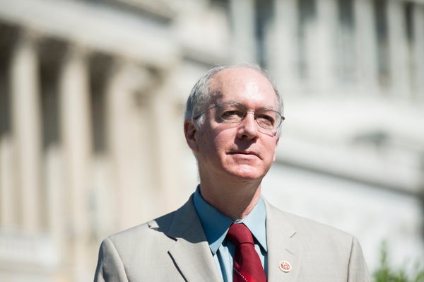 Bill Foster in a suit and red tie, standing in front of a government building.