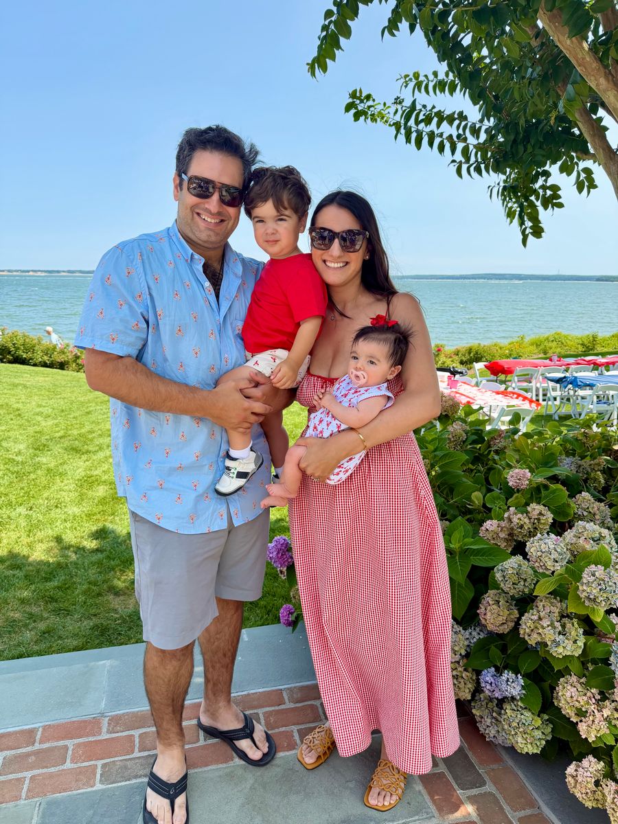 A family of four people stands together in a beach location