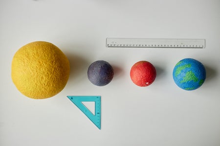 A rule and angle measure next to models of the sun and planets