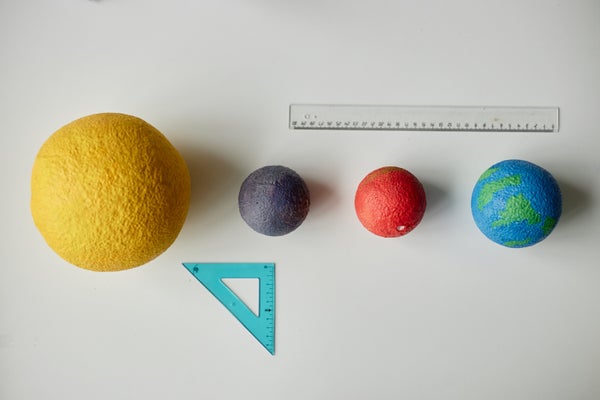A rule and angle measure next to models of the sun and planets