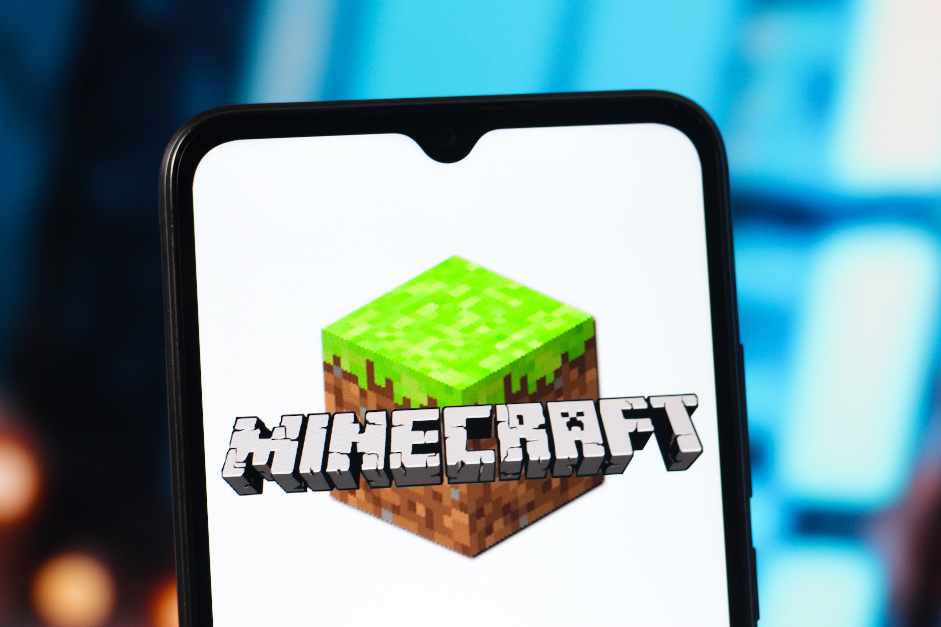 The Minecraft logo is seen on a mobile device's screen.