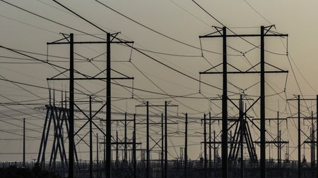 Power lines and electricity transmission towers against a sunset or sunrise