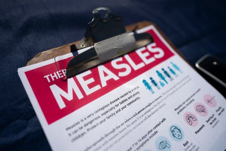 A bright red-and-white fact sheet for measles on a clipboard