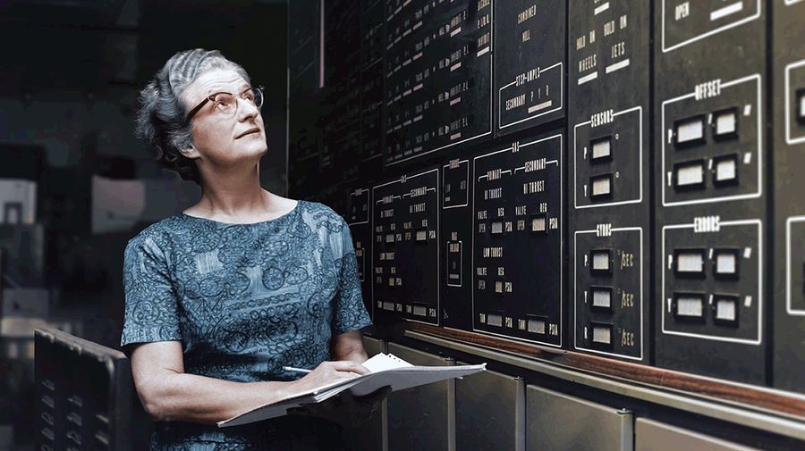 A woman with glasses and gray hair looks up at a wall of computer instrumtation. Image provided by NASA/Interim Archives/Getty Images.