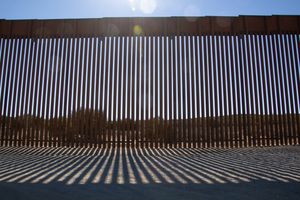 A tall slatted fence across the U.S.-Mexico border.