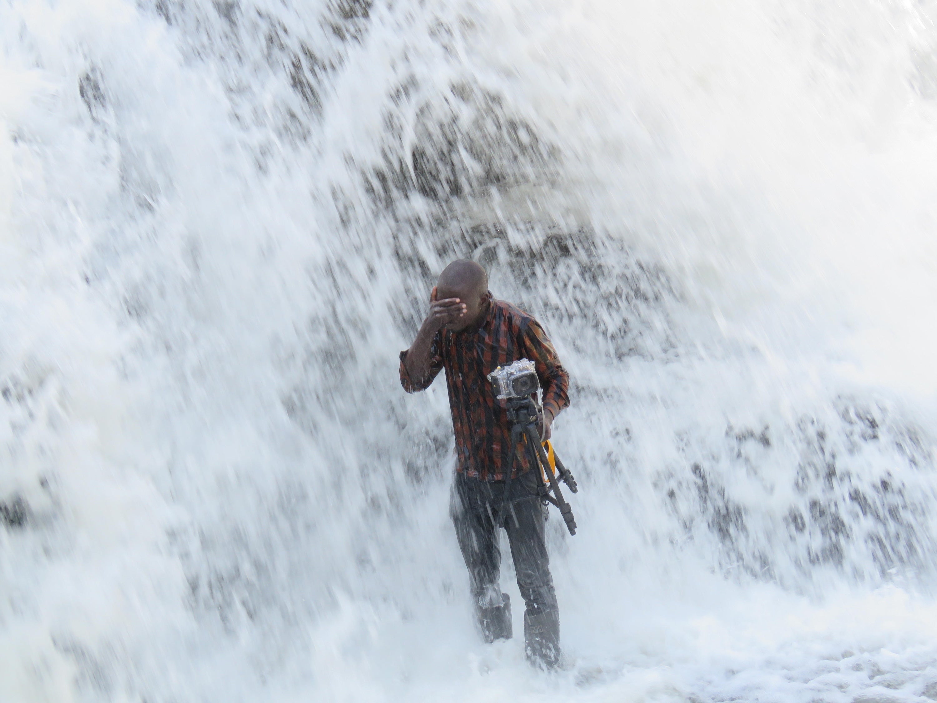 شخص يغطي عينيه أثناء الاستحمام بالماء ويحمل كاميرا.