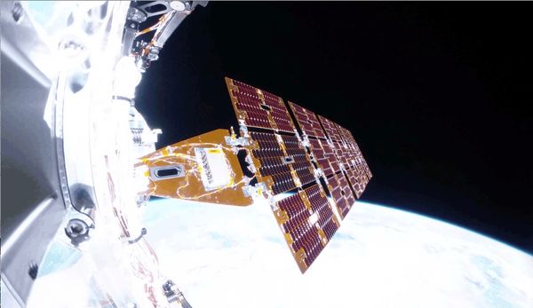 A view of a spacecraft deploying solar arrays with the Earth in the background.