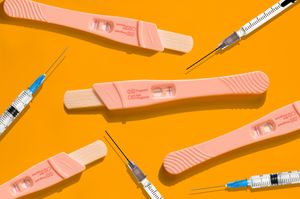 Pregnancy tests and syringes against a yellow background