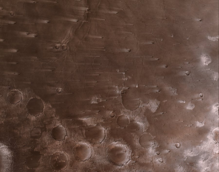This view of the Martian surface shows streaks that have formed due to wind blowing over impact craters in the Syrtis Major region.
