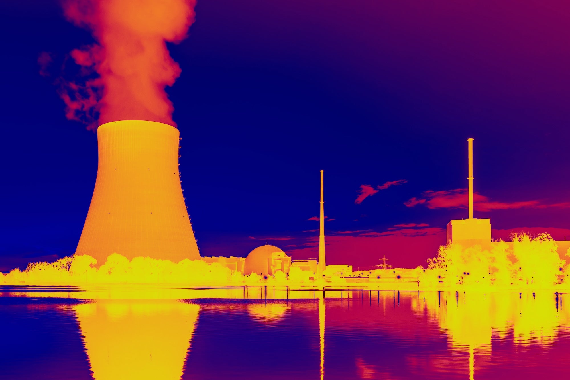 A thermal infrared photo of a nuclear power plant, with the plant appearing in yellows and oranges and the surround sky and river in the foreground in deep purple