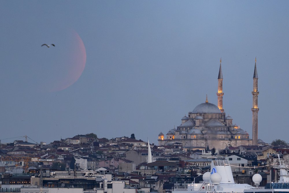 A faint red moon above a mosque.