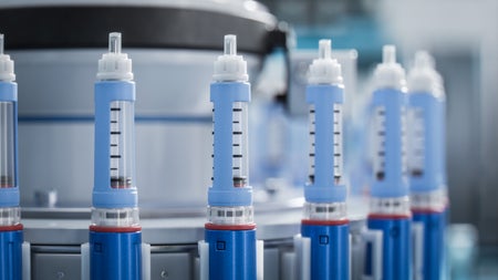 Close-up of a blue medical injector on a conveyor line during the production process at a modern pharmaceutical factory.