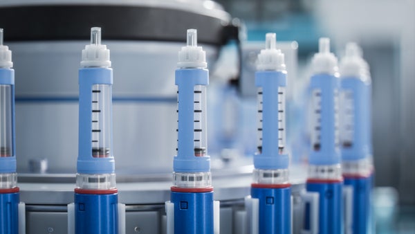 Close-up of a blue medical injector on a conveyor line during the production process at a modern pharmaceutical factory.