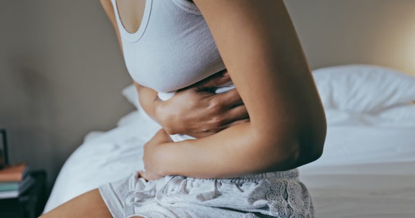 Cropped image of young woman holding her stomach.