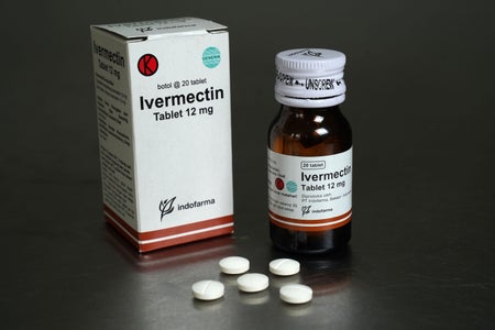 Ivermectin tablets arranged in front of a package and bottle