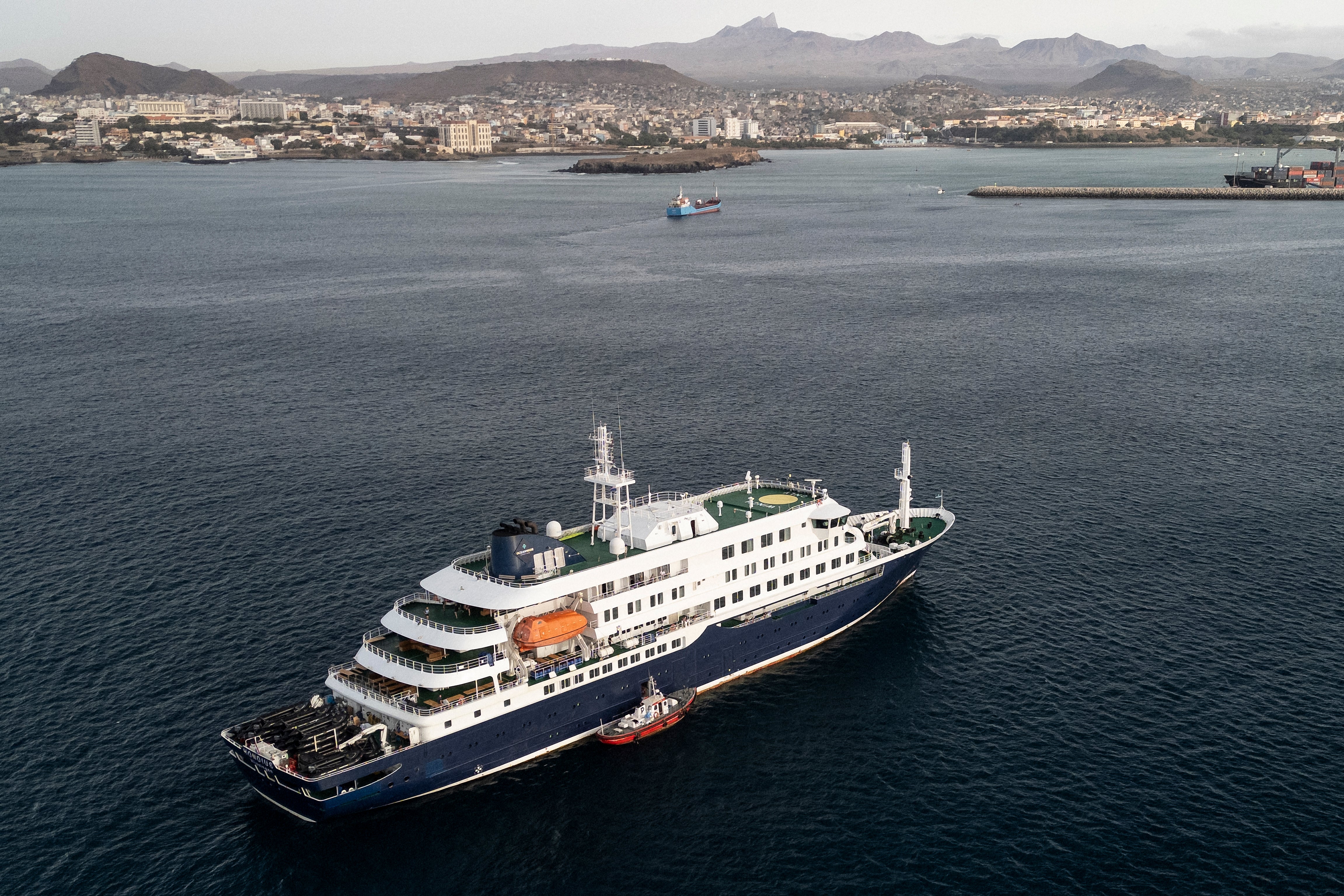 This aerial view shows health personnel boarding the cruise ship MV Hondius, while stationary off the port of Praia, the capital of Cape Verde, on May 6, 2026.