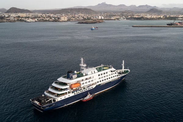 This aerial view shows health personnel boarding the cruise ship MV Hondius, while stationary off the port of Praia, the capital of Cape Verde, on May 6, 2026.