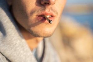 Close-up of an unrecognizable man smoking a joint at sunset.