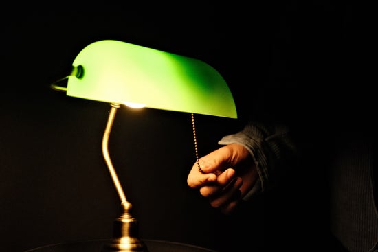 A person turning on and off a desk lamp