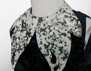 A green- and white-splattered collar on a shirt made of fungus.