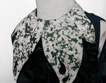A green- and white-splattered collar on a shirt made of fungus.