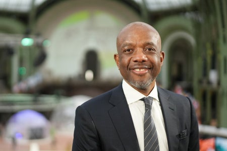 James Manyika in a suit, smiling into the camera, at the Artificial Intelligence Action Summit in Paris.