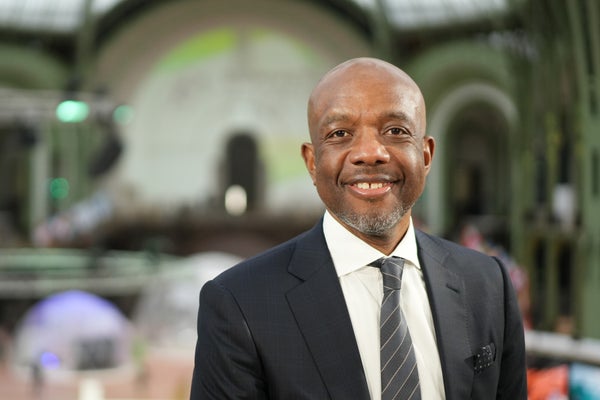 James Manyika in a suit, smiling into the camera, at the Artificial Intelligence Action Summit in Paris.