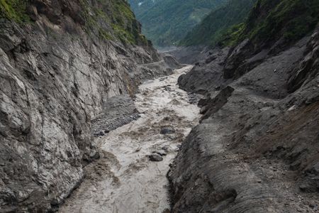 An aerial view shows a torrent of muddy water surging through a river.