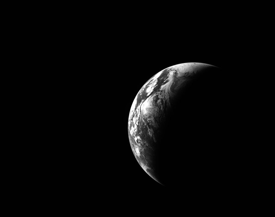 A black-and-white view of a crescent Earth, as seen from space.
