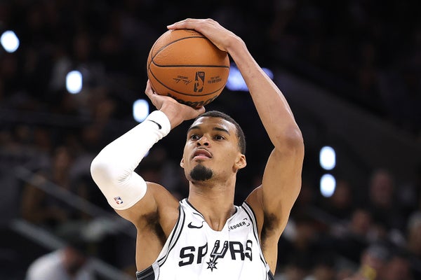 A man holds a basketball over his head and prepares to shoot.