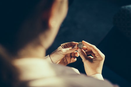 A person looks at a 1 euro coin in their hands