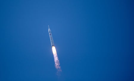 A Chinese Long March 10 rocket soars through a clear blue sky on a fiery exhaust plume