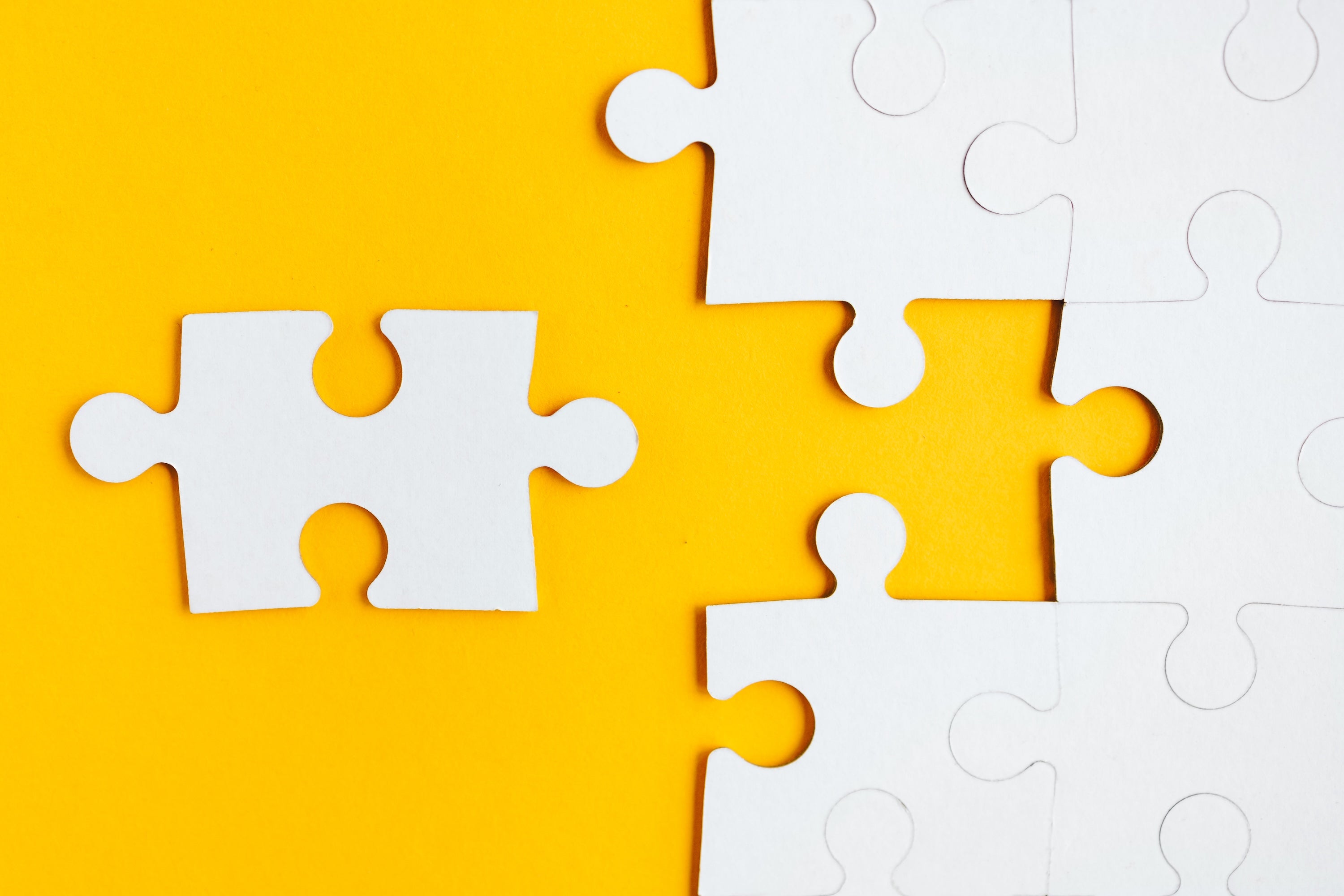 A white puzzle piece is arrayed near a gap in other white puzzle pieces.