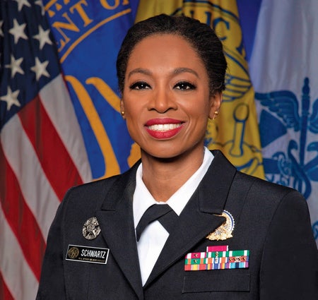 An official portrait of a smiling woman in a Naval uniform.