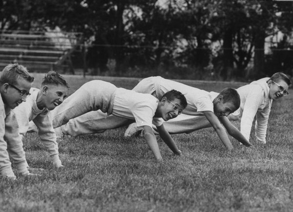 Five boys doing push ups on grass, archival photograph from the 1960s