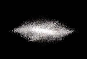 A scattering of table sugar against a black background.