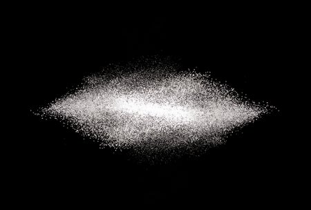 A scattering of table sugar against a black background.