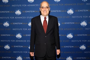 Edward Witten in a suit, standing against an Institute for Advanced Study Einstein Gala background.