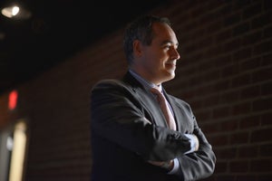 Ángel Cabrera standing in a suit, with his arms crossed, looking to the side.