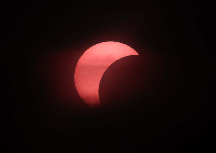 Solar eclipse showing a pink crescent