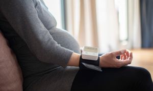 Image of pregnant woman wearing a blood pressure cuff on her wrist.